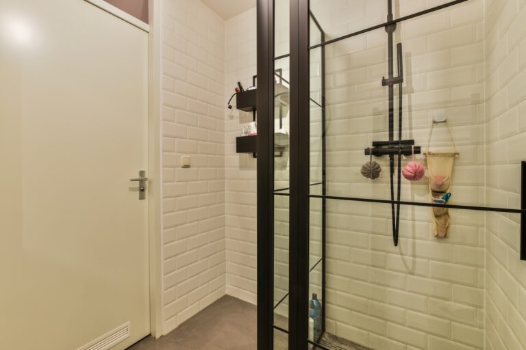 a shower with white tiles and a glass door