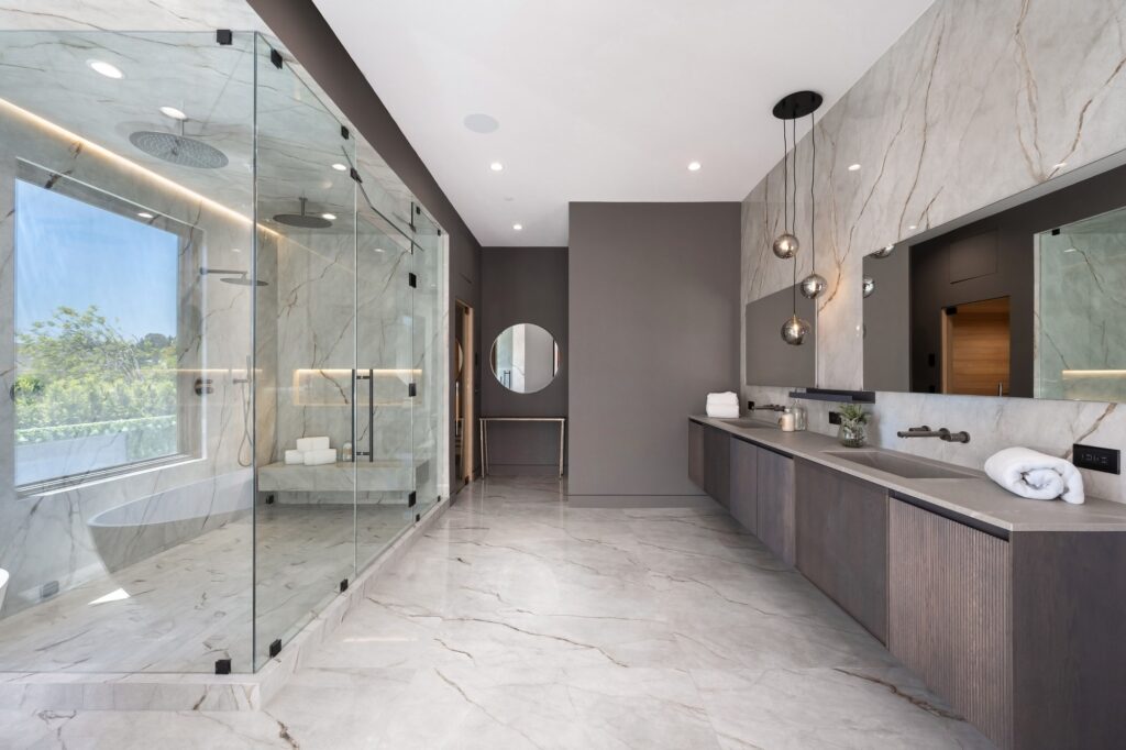 Luxurious modern bathroom with marble walls and glass shower.