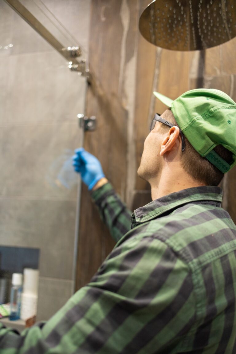 Workers are installing glass door of the shower enclosure.